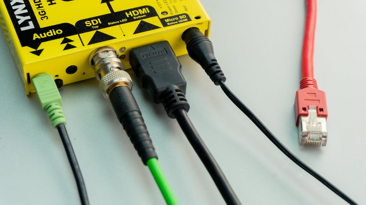 A close-up view of different cables including HDMI, Ethernet, and audio connected to a yellow device.